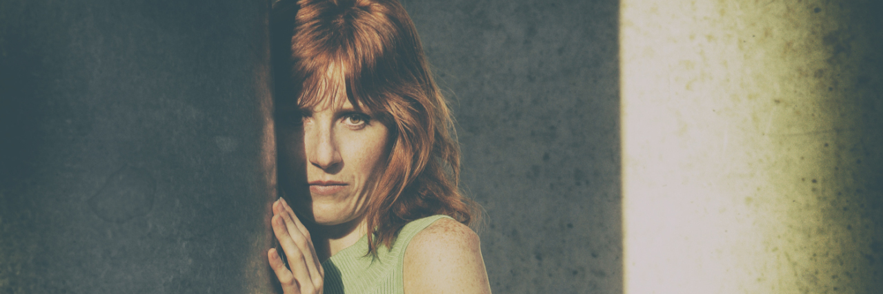 Asperger's and 'Passing' as Non-Disabled Woman standing behind pillar.