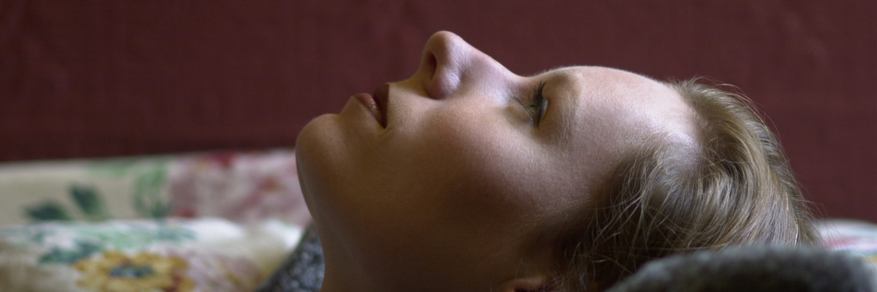 woman lying on her back in bed staring at the ceiling