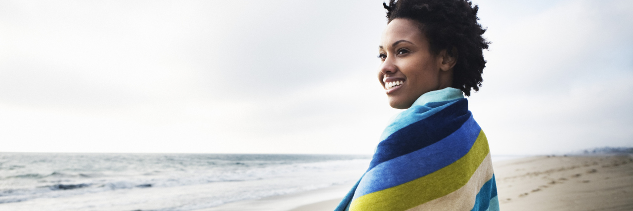 Epilepsy: Creating Goals in Physical Therapy Based on My New Normal woman standing on a beach wrapped in a towel