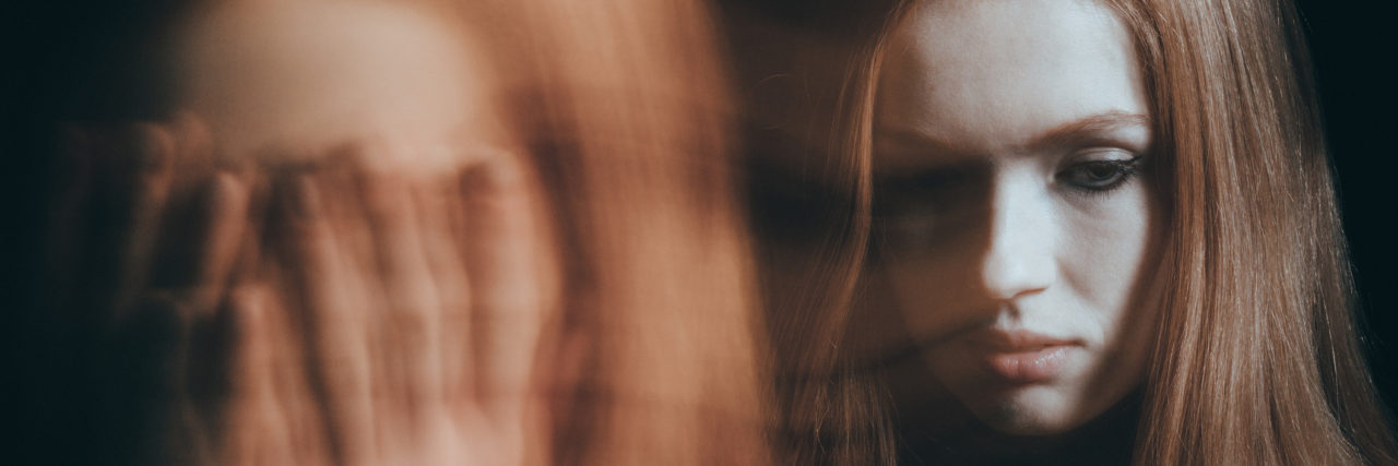 When You Have a Phobia of Others Hearing Your Voice Stressed, young woman covering her face, dark background