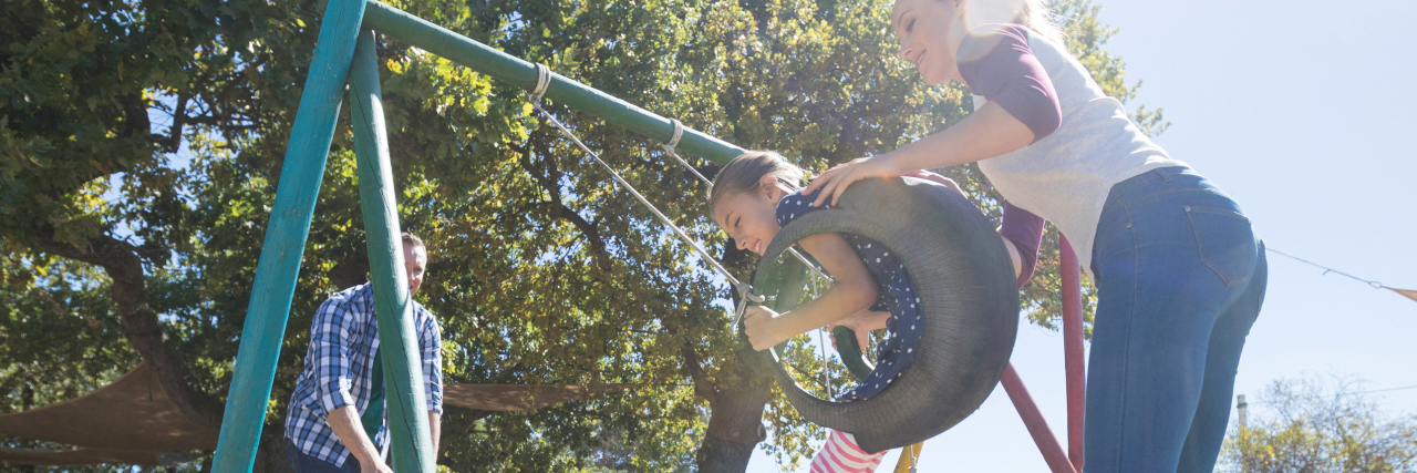 Tips for Coping With Sensory Processing Disorder as an Adult Happy parents pushing children sitting on swings at playground on a sunny day.