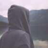 woman wearing a hoodie and standing outside near a lake