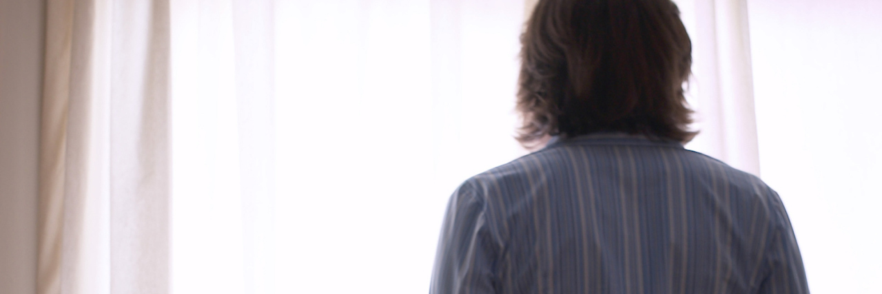 Why Home Is the Only Place I Feel Safe After My Stroke Woman looking out window at home