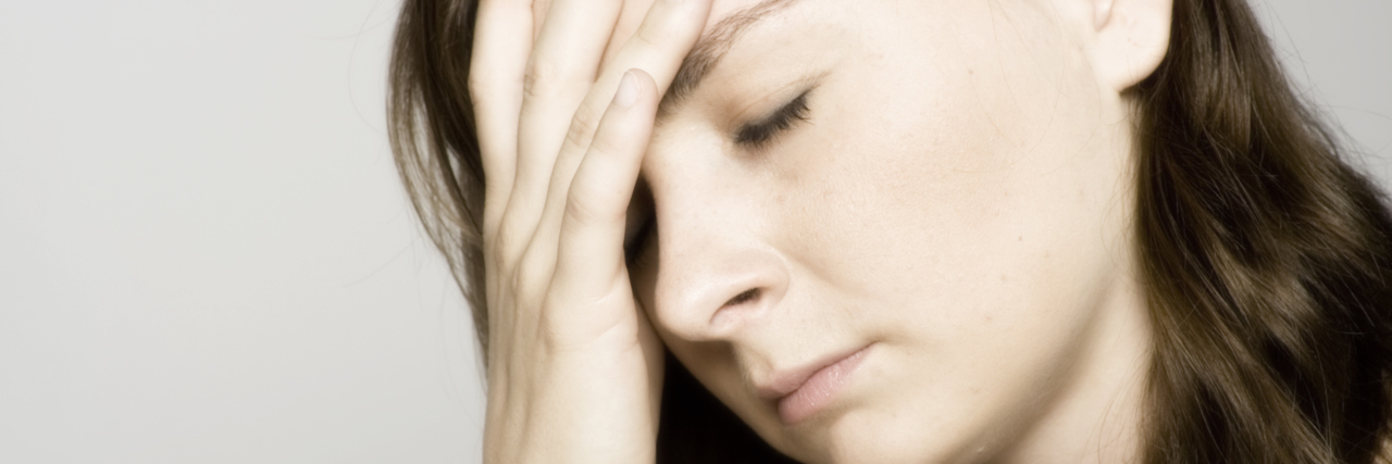 What a Trigger Actually Is With Chronic Illness and Migraine woman holding her head in pain