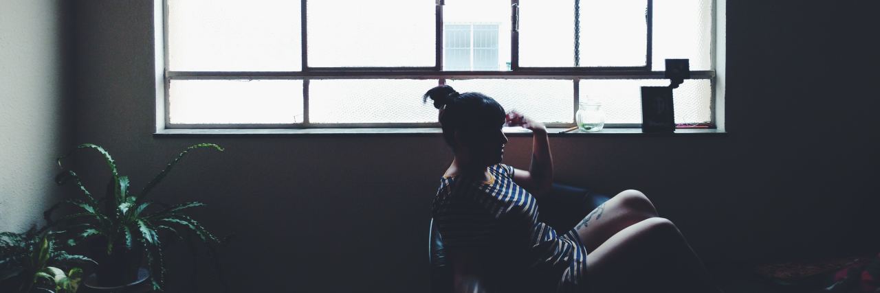 I'm Suicidal, but Every Day I Make the Choice to Stay a woman sits in a chair in front of a bright window
