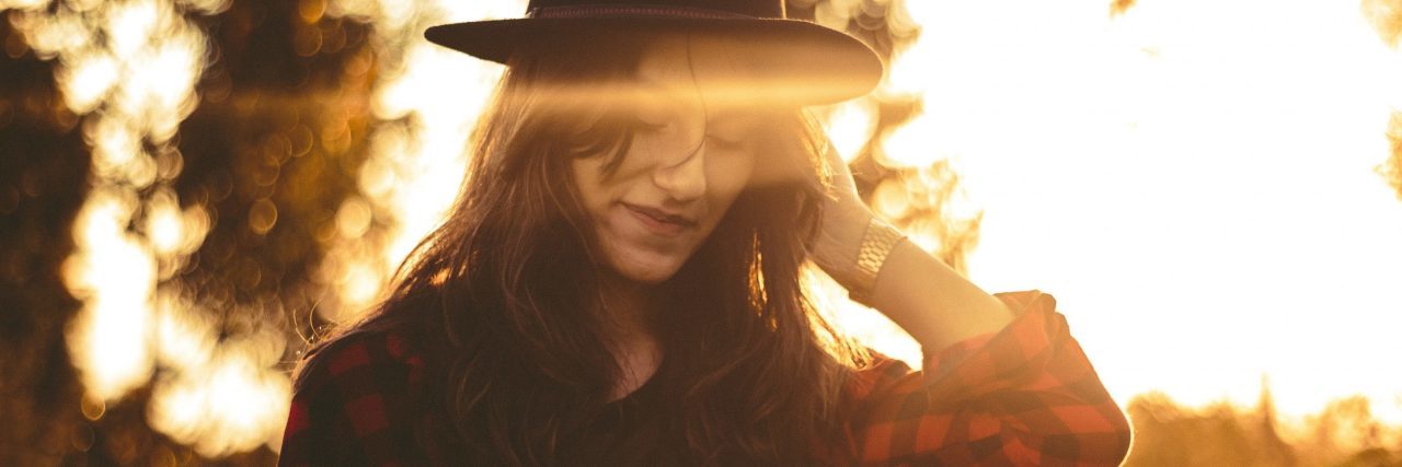 My Experience With Electroconvulsive Therapy for Bipolar Disorder dark haired woman wearing hat smiling sunset