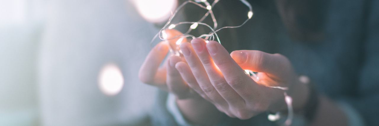 young woman's hands holding fairy lights in delicate way