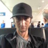 man sitting in an airport wearing a hat