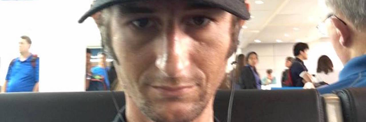 Flying and Traveling With Short Bowel Syndrome man sitting in an airport wearing a hat