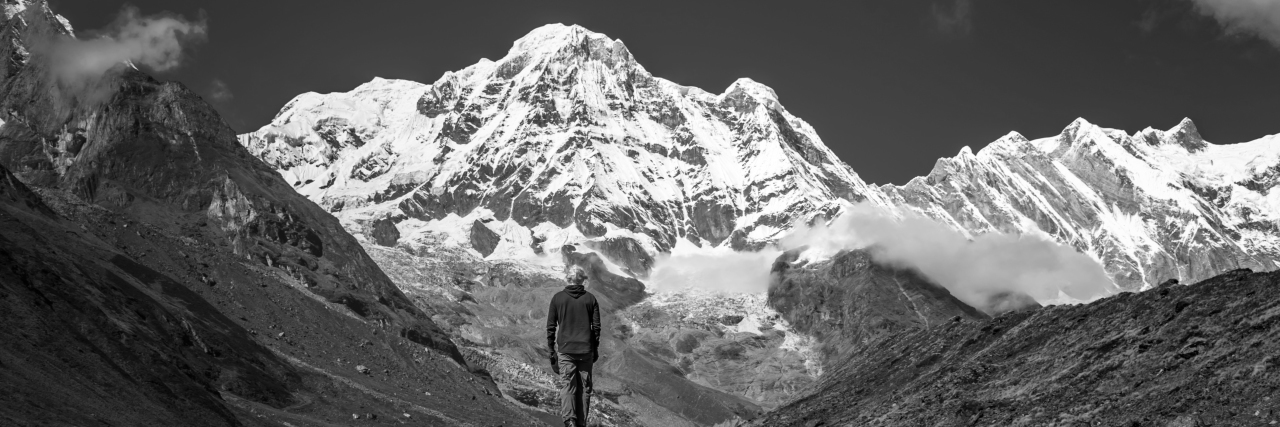 person standing in front of himalayan mountains in black and white