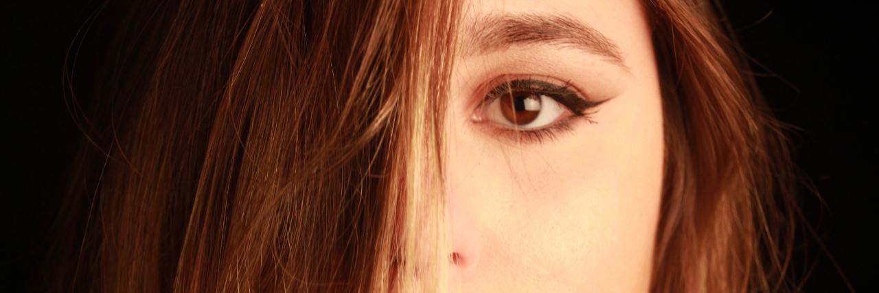 I Won't Say Sorry for Struggling With Mental Illness Anymore woman with half of face covered by hair. red lipstick and winged eyeliner