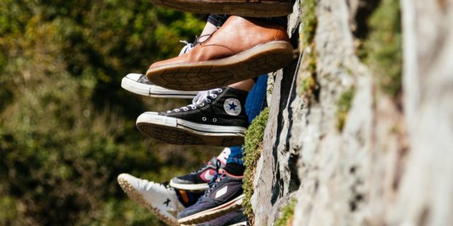 peoples feet dangling as the sit on a wall