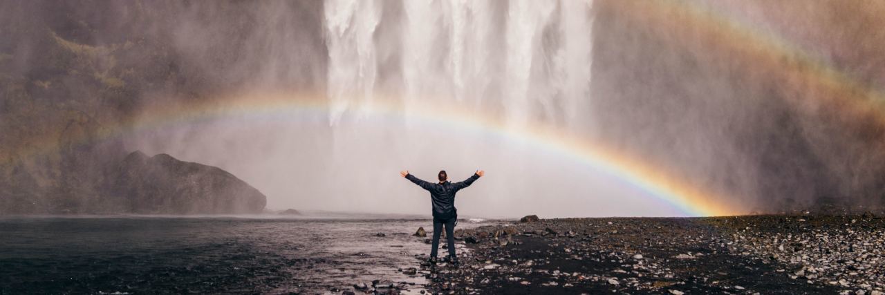 How Accepting My Dysautonomia Helped Me Embrace My New Life person standing in front of a waterfall with a rainbow overhead