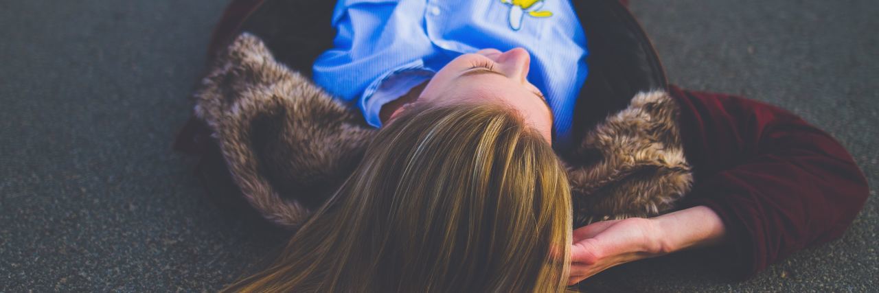 There Is So Much More to My OCD Than Most People Know woman lays in the middle of a road