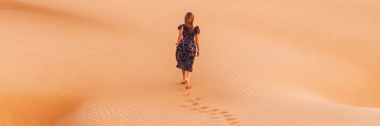 woman walking through desert leaving footprints behind