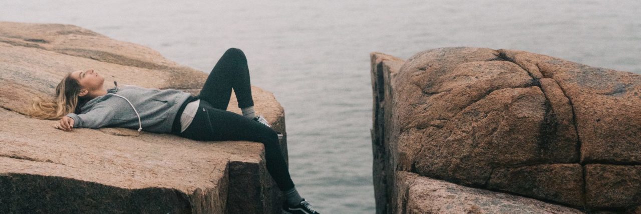 When Past Trauma Means You Don't Have Many 'True' Friends woman on cliff lying back listening to music