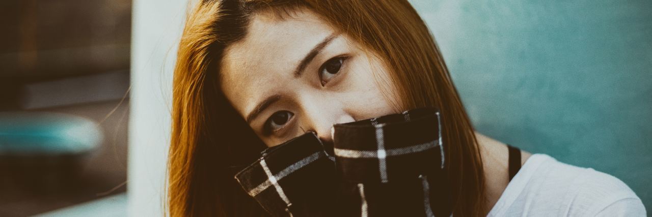 When Mental Illness Makes You Your Own Worst Enemy a woman covers her mouth with her shirt