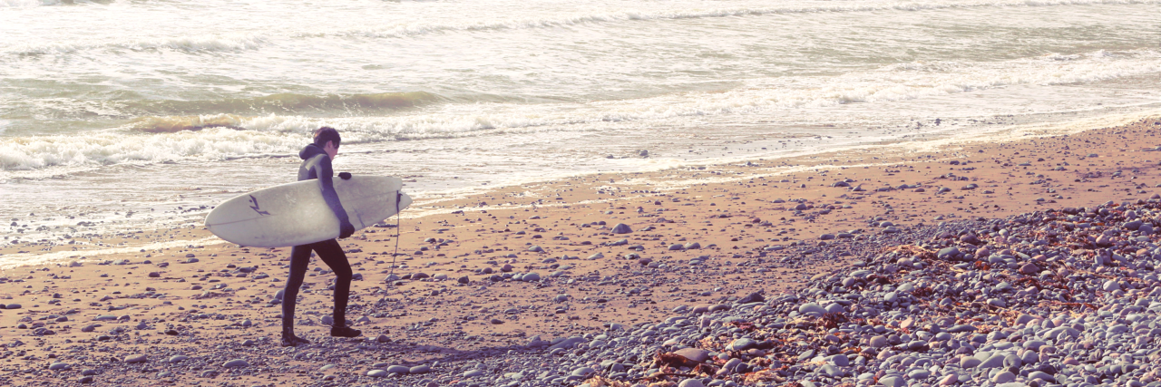 Major Accomplishments When Struggling With Depression person with surfboard walking along hazy beach
