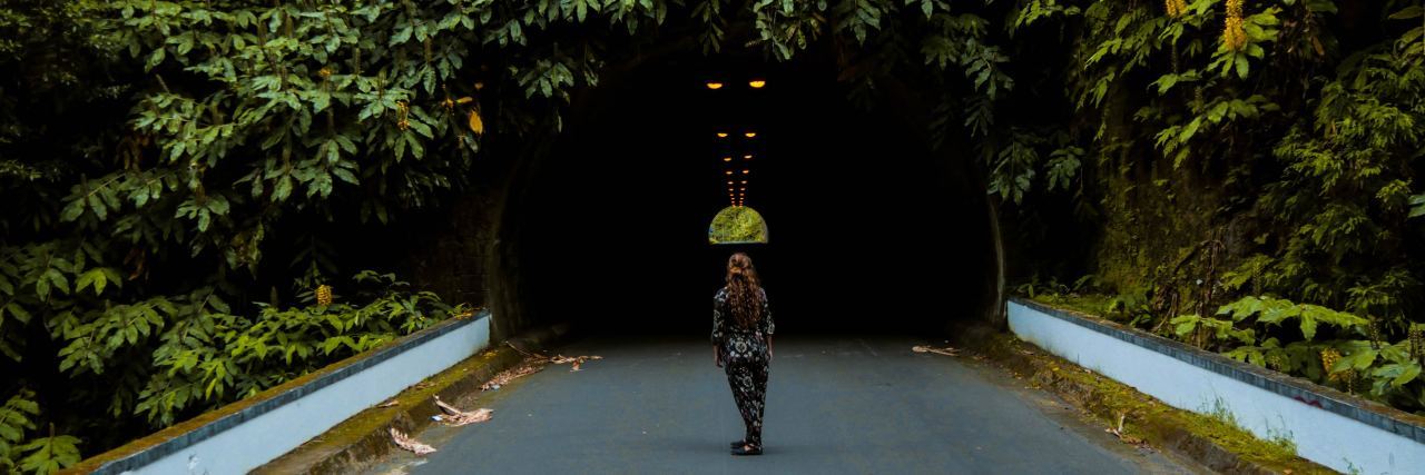 How I'm Growing Through the Pain of Post-Traumatic Stress Disorder woman stands in front of a bridge covered in vines