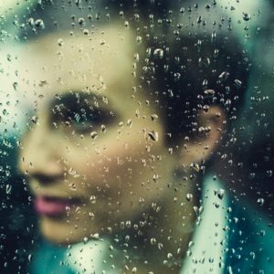 soft focus of woman with focus on raindrops on window