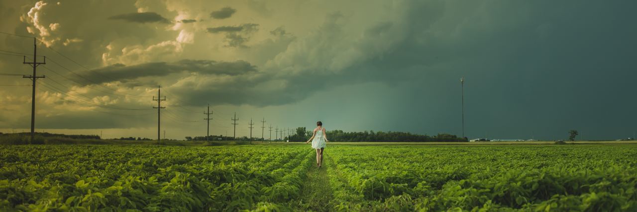 What a Bipolar Disorder Mood Swing Feels Like woman in field looking at storm on horizon