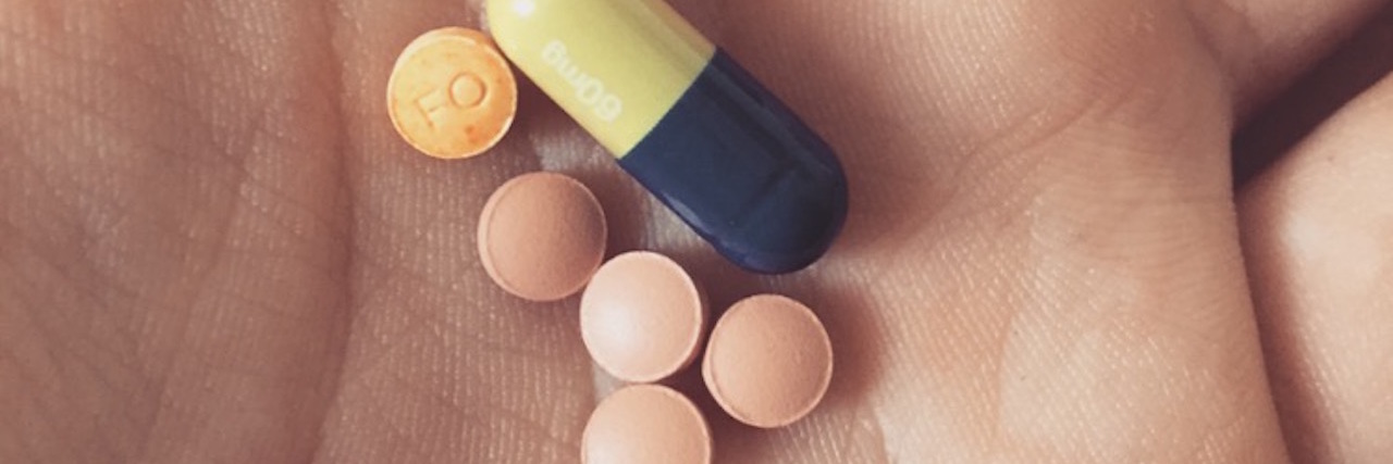 Please Stop 'Pill Shaming' People With Anxiety and Depression person holding medicine in their hand