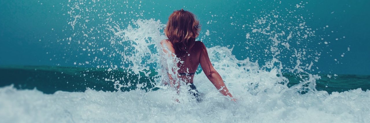 woman standing happily in wave as it crashes over her