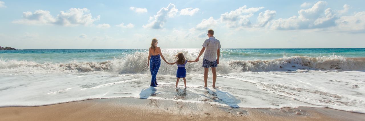 We Need to Discuss My Preteen Daughter’s Hospitalizations mother father and daughter standing in waves at beach looking out to sea