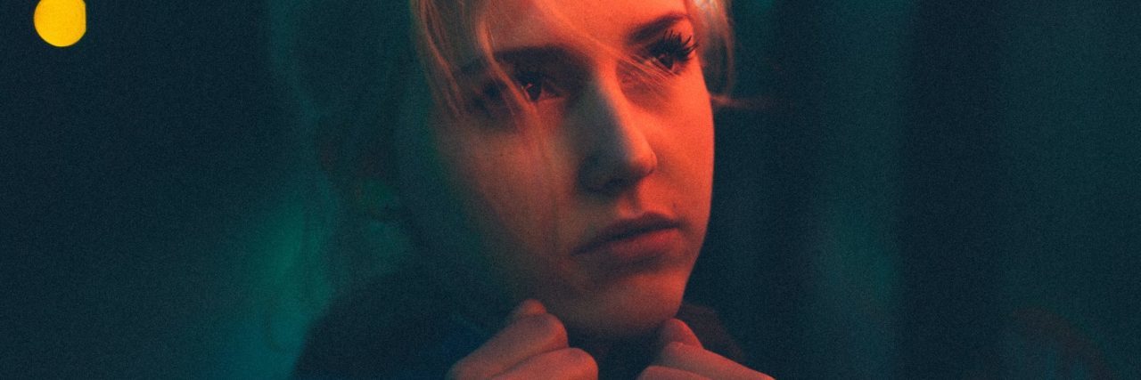 When Depression and Anxiety Walk Hand-in-Hand young woman in darkness with fists pressed to chin looking off into distance