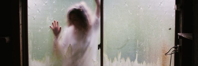 woman on other side of frosted window pressed against glass