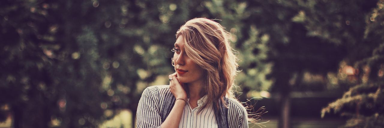 I Am a Life Coach With OCD, and I Don't Have My Shit Together a woman with blonde hair and red lipstick stands between trees