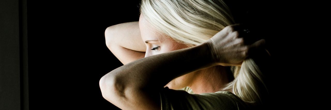 Why We Must Treat Mental Health as a Sliding Scale woman stands pulling her hair back