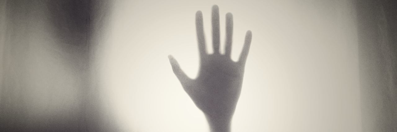 Why My Dermatillomania Is Worse When I'm Not Doing Well a hand pressed against a foggy pane of glass