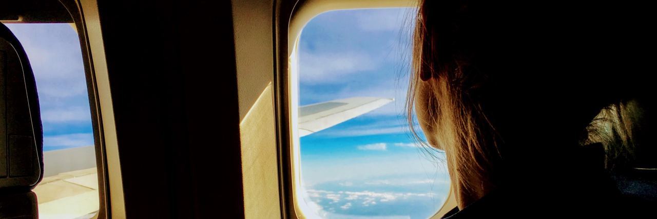Why We Need 'Mental Health Vacations' woman looking out a plane window watching the clouds