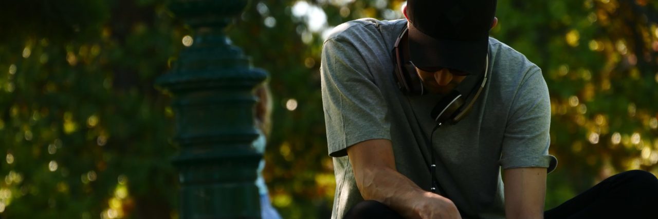 Things I Realized in the Years Following My Suicide Attempt man in park wearing hat writing in book