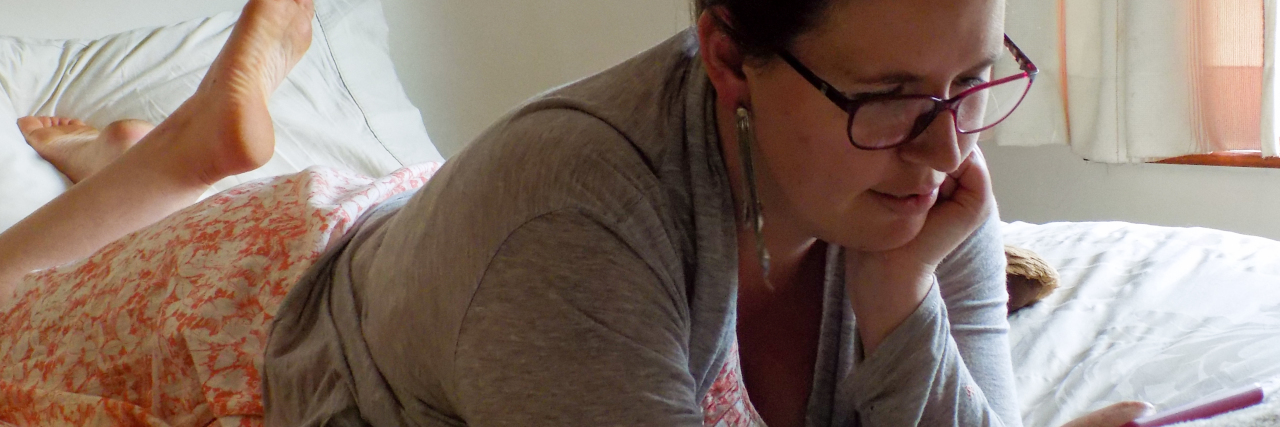 How Reading Books Helps Me Cope With Chronic Pain From CRPS woman reading a book on her kindle in bed
