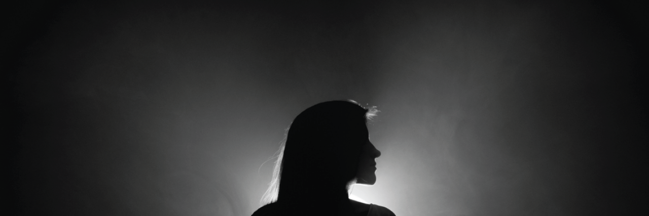 How People Reacted to Their Borderline Personality Disorder Diagnosis woman stands in dark with light shining behind her
