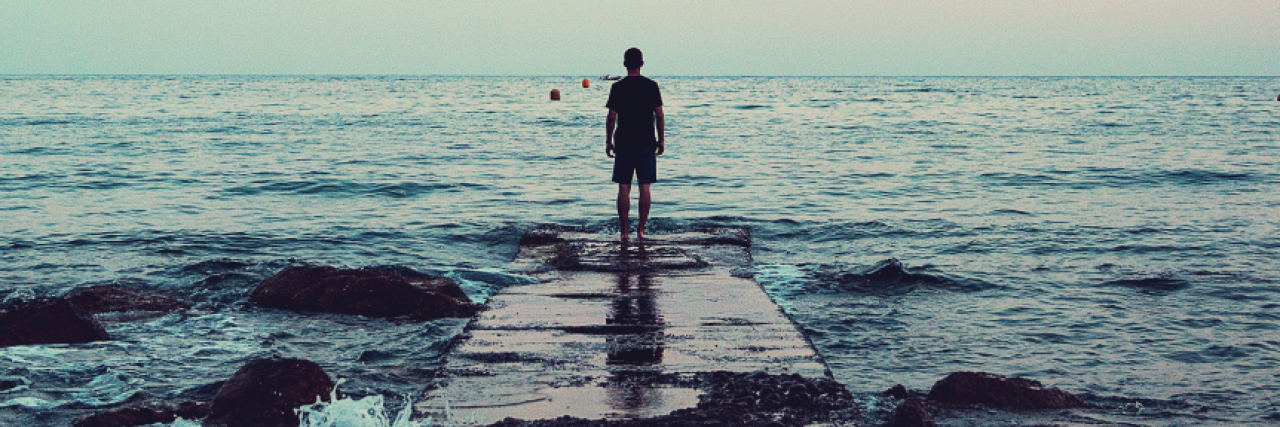 44 Unexpected Coping Techniques for People With Mental Illness man stands at the end of a dock surrounded by water and the sunset