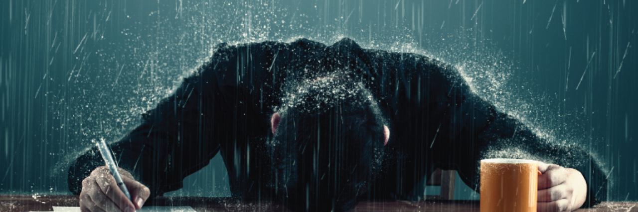 Ways to Take Care of Yourself If You Can't Afford a Mental Health Day man with head on desk and rainclouds over head