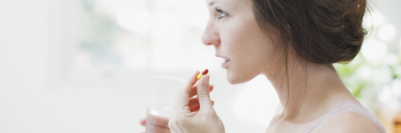 How Medication for My Mental Health Saved My Life woman holding pill and glass of water