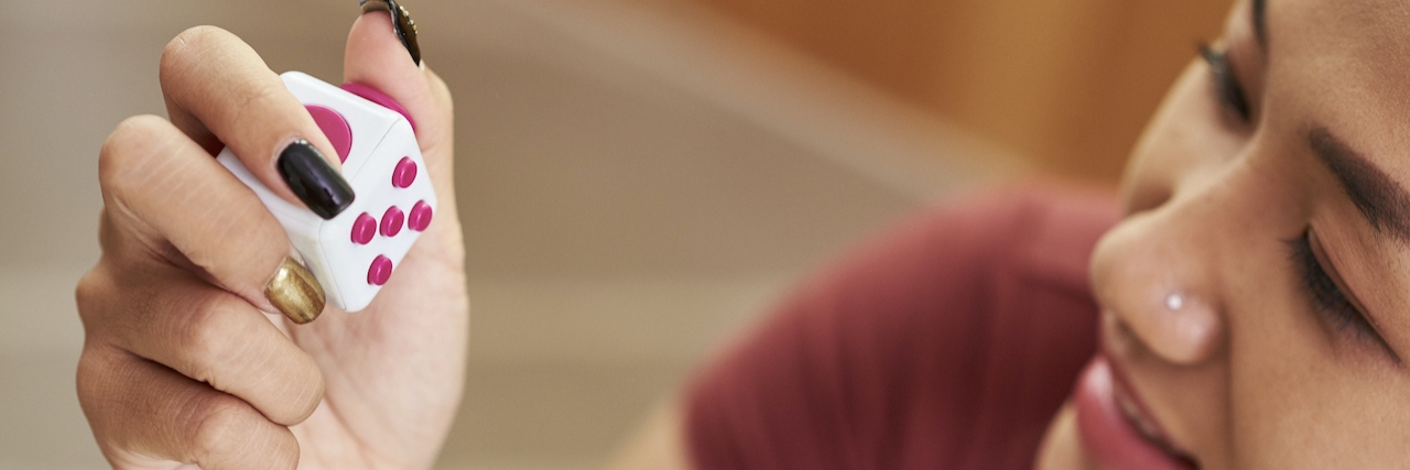 5 Fidget Toys for Compulsive Skin Picking Woman holding fidget cube