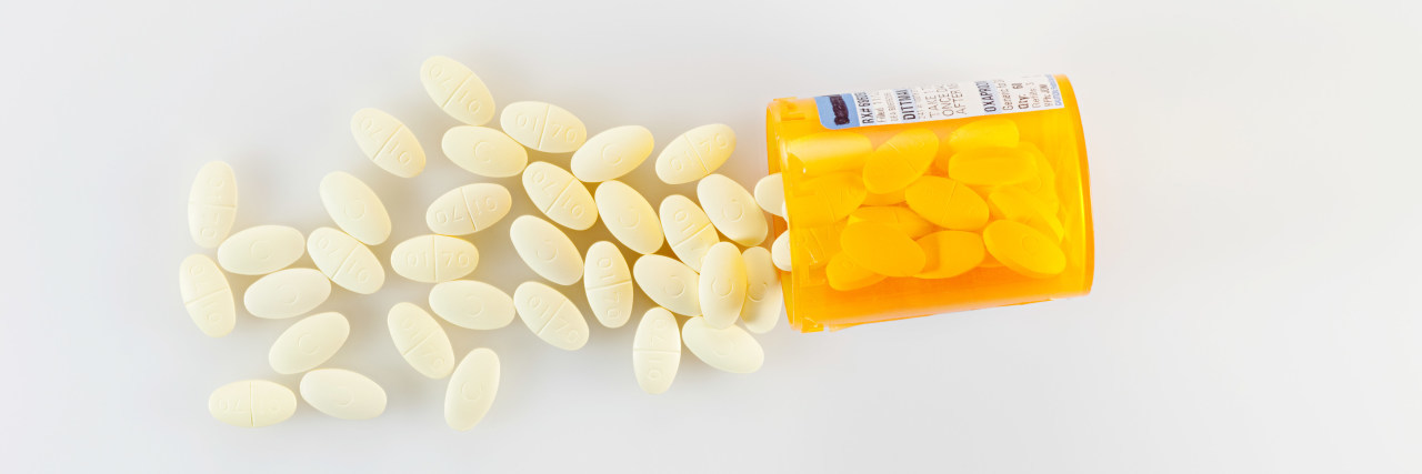 The Problem With Doctors Encouraging 'Pain Acceptance' on Vox Podcast pills spilling from container