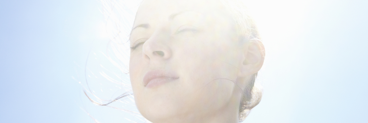 Choosing to Be Visible With Lyme Disease woman smiling with the sun right behind her