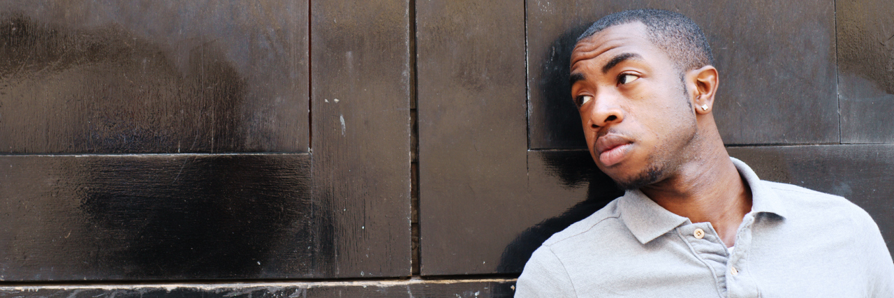 Why I'm Speaking Out About My Mental Health Journey young black man leaning on door looking away from camera