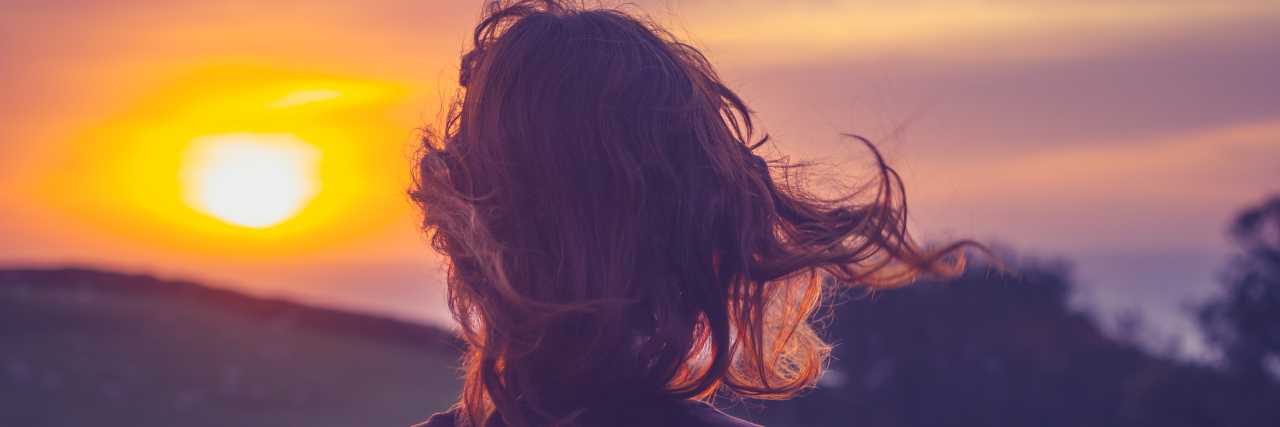 A Few Critical Things That Helped Me Survive Pancreatic Cancer Young woman admiring the sunset over fields