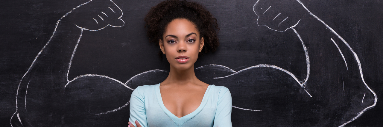 Being Validated by Doctors After Fighting for Your Health woman crossing her arms against a chalkboard with muscled arms flexing