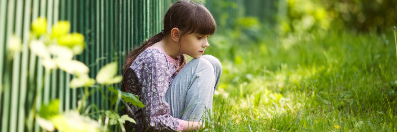 Sad girl sitting on the grass.