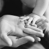 Closeup of baby's and parent's hands. black and white picture