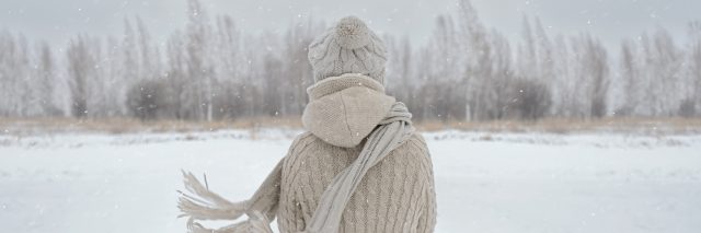 Unrecognizable woman stands back in the woods in winter