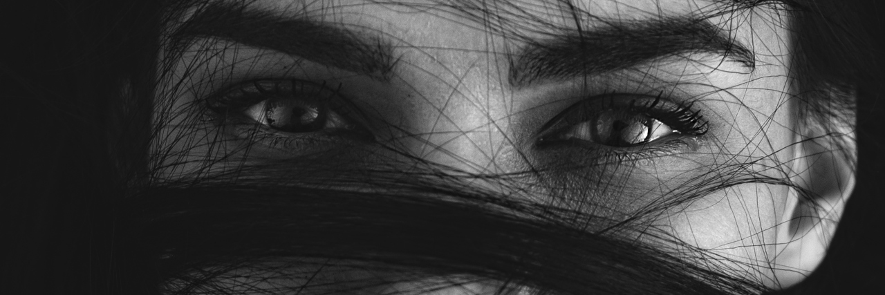 3 Things I Wish I Had Known About OCD Treatment Portrait of a mysterious woman with her long brown hair wrapped in strands across her face looking at the camera with seductive luminous eyes, monochrome head and shoulders image
